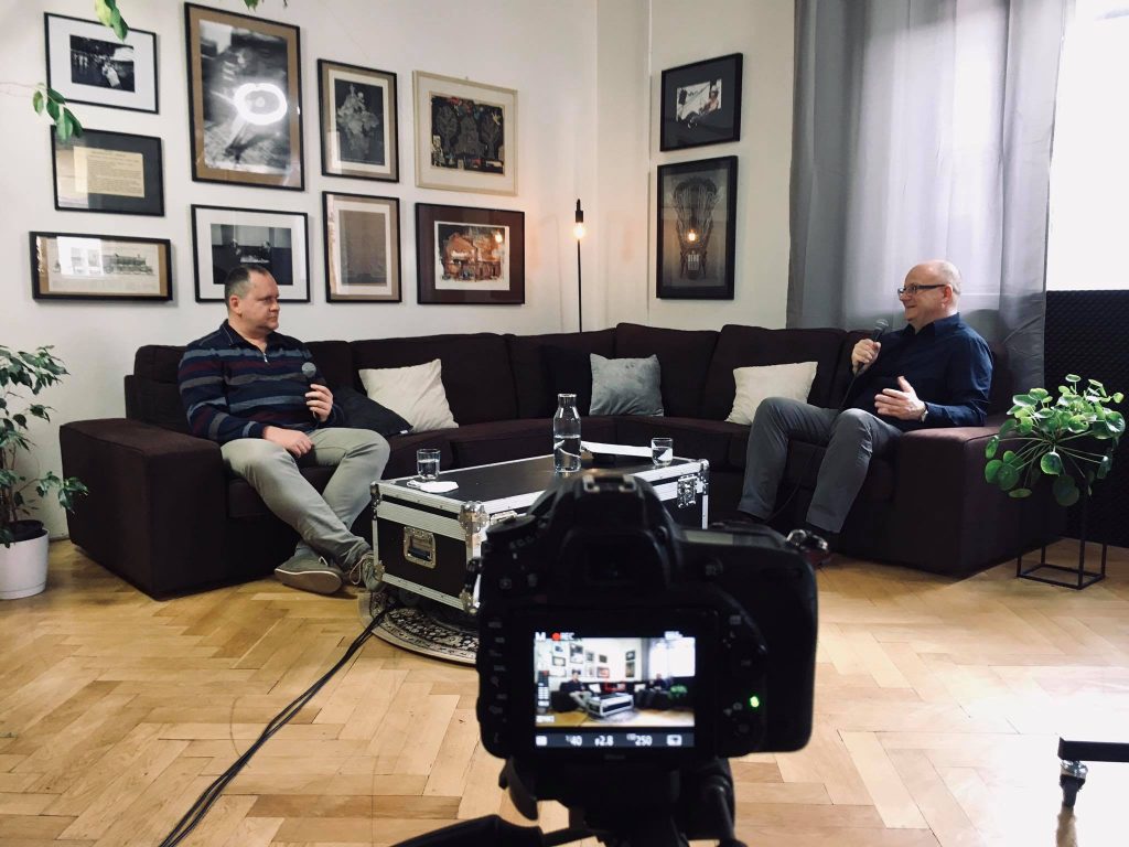 Branislav Moťovský a Ivan Ježík sediaci na gauči počas rozhovoru, v popredí fotoaparát